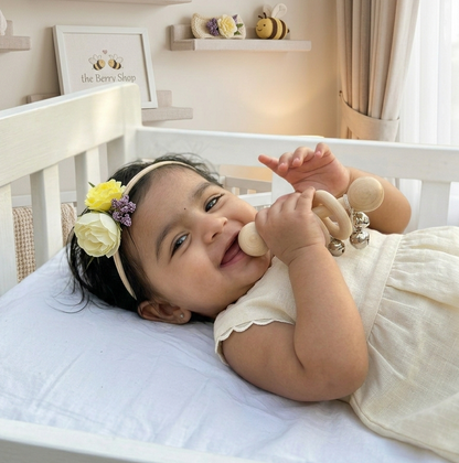 Cream and pastel yellow floral hair clip with green leaves and lilac accents for baby girls on Berry Shop display card.
