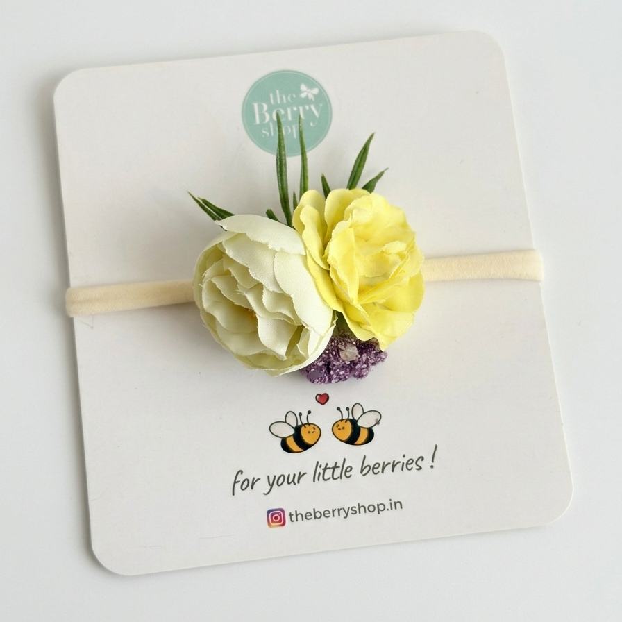 Cream and pastel yellow floral hair clip with green leaves and lilac accents for baby girls on Berry Shop display card.
